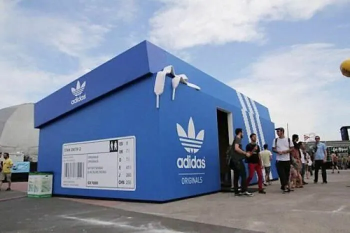 Adidas shoe box shaped building with brand logo and people nearby