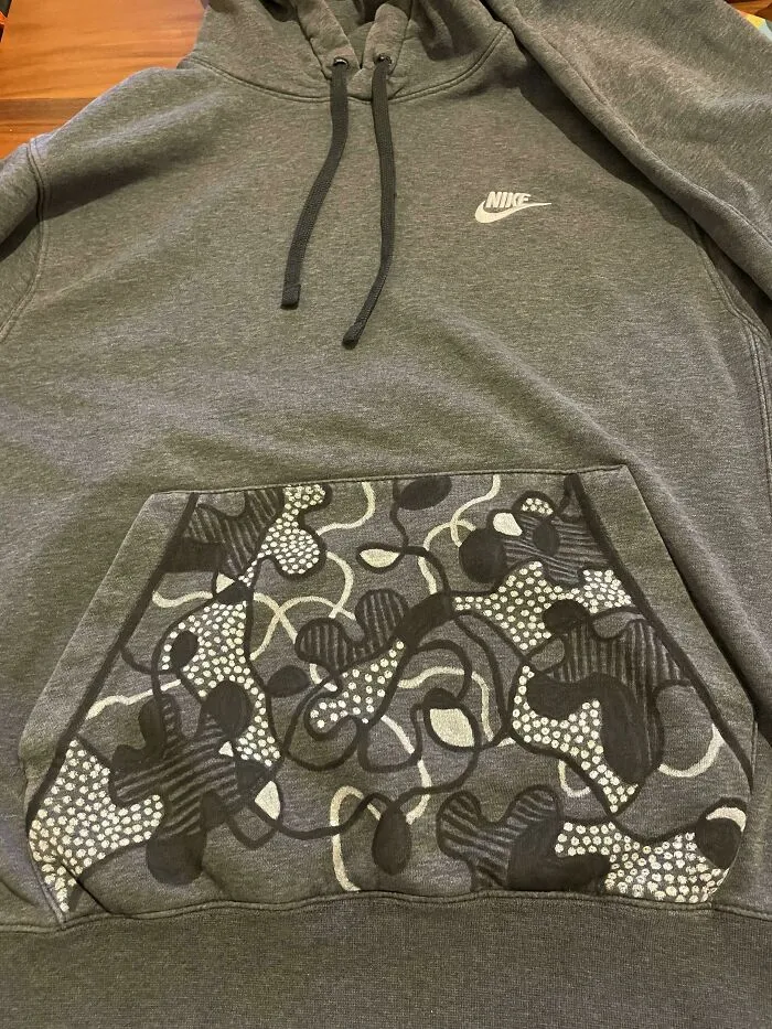 Grey Nike hoodie with custom camo pattern hand drawn on front pocket showing creativity to save money.