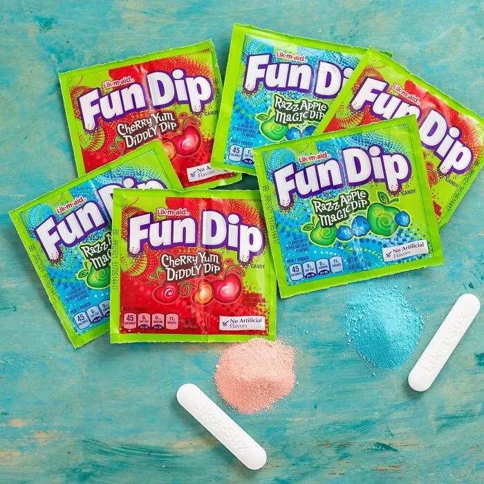 Pouches of Fun Dip candy with edible sticks and candy powder on a turquoise background for Best Halloween Candies.