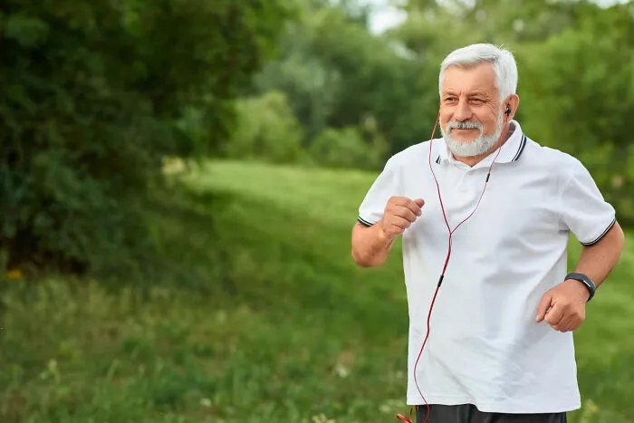 A senior man jogging outdoors listening to music, reminding us of unexpected moments at funerals.