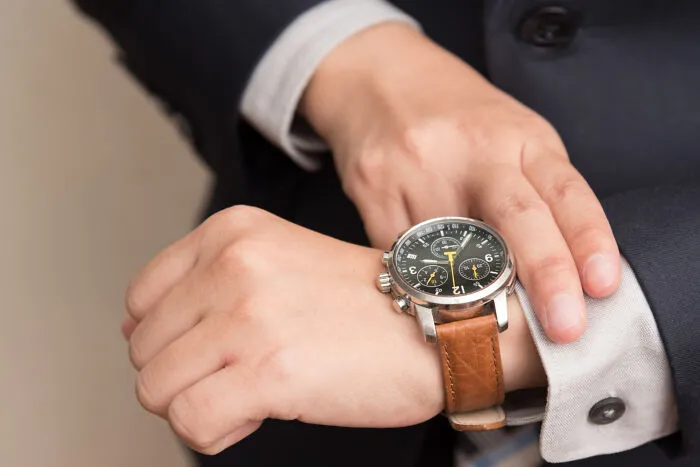 Close up of a businessman checking his wristwatch, illustrating obvious lies about being late.