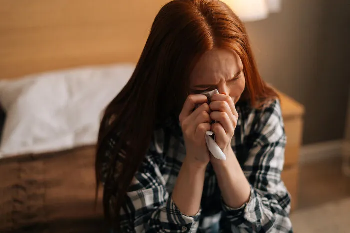 Distressed woman crying into a tissue, representing painful divorce stories.
