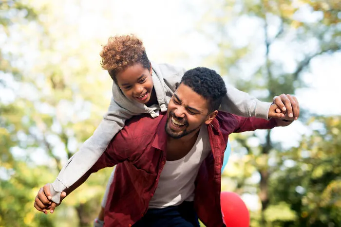 A father giving his daughter a piggyback ride, showing the bond before lifelong friendships fizzle out.