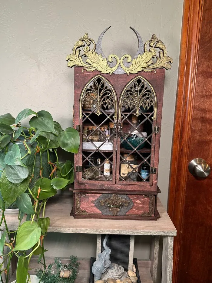 Gothic style mini cabinet displaying potions on a table for a home makeover.