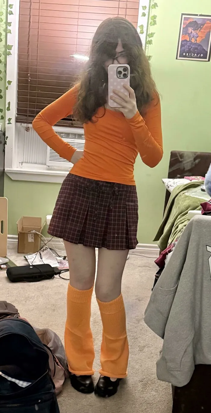 Young woman posing in a Velma-inspired orange sweater and skirt creative Halloween costume