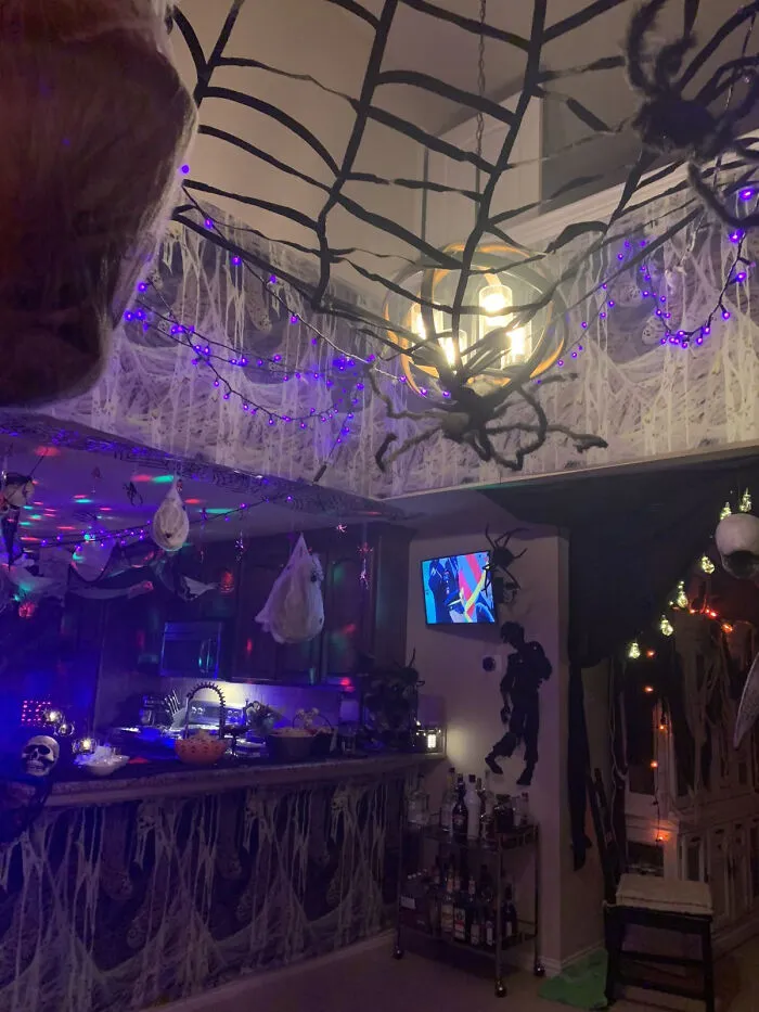 Indoor room covered in giant cobwebs and purple lights as Halloween home decorations.