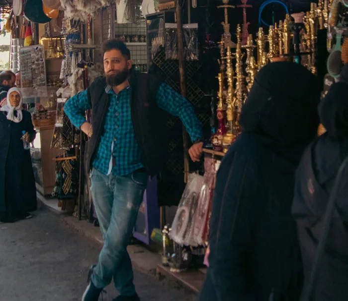 Man leaning against a shop front looking at strangers, causing fight-or-flight to activate