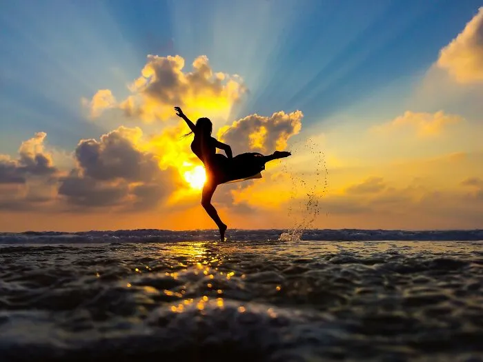 Silhouette figure kicking water at sunset vibrant sky iPhone image