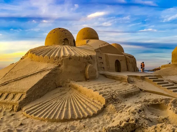Sandcastle shaped like a building at sunset captured with iPhone photography