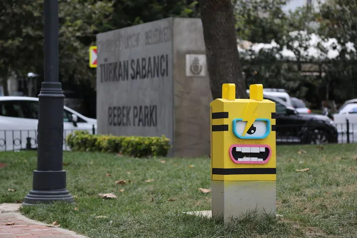 A yellow character post on city streets showing creative art collective pop culture designs.