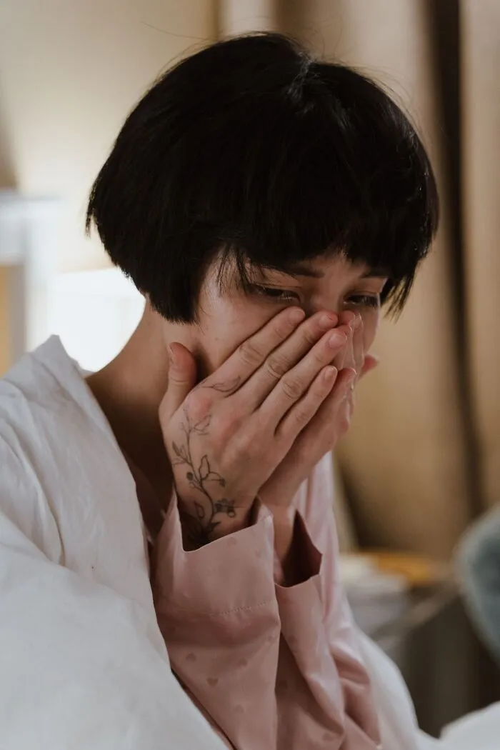 An upset woman covering her face in tears, experiencing emotional turmoil before deciding to choose divorce.