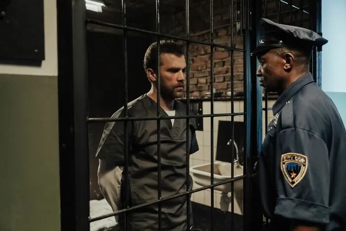 Prisoner and police officer talking through jail cell bars