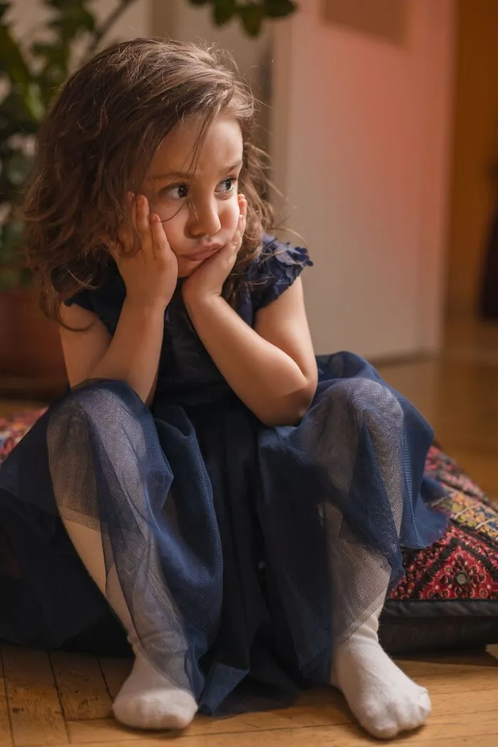 A sad young girl resting her head on her hands, showing the emotional impact of choosing divorce.