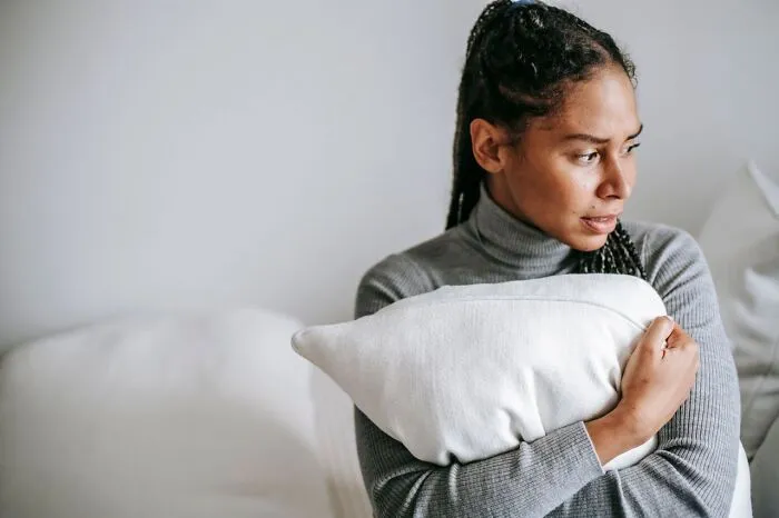 A worried woman hugging a pillow tightly while facing relationship issues and divorce
