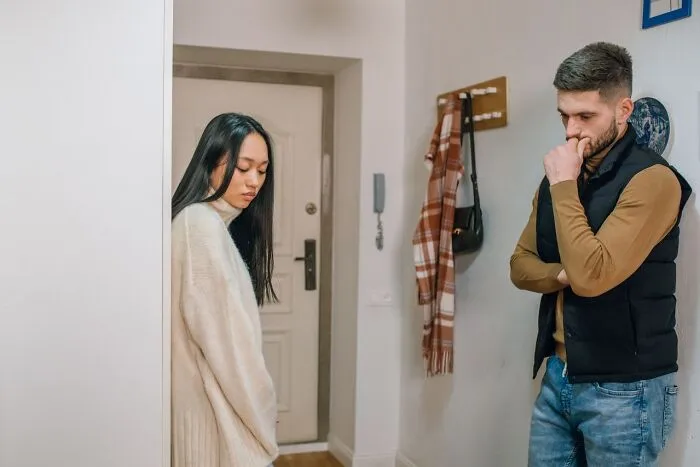 A distant couple standing apart in a hallway considering divorce over staying together
