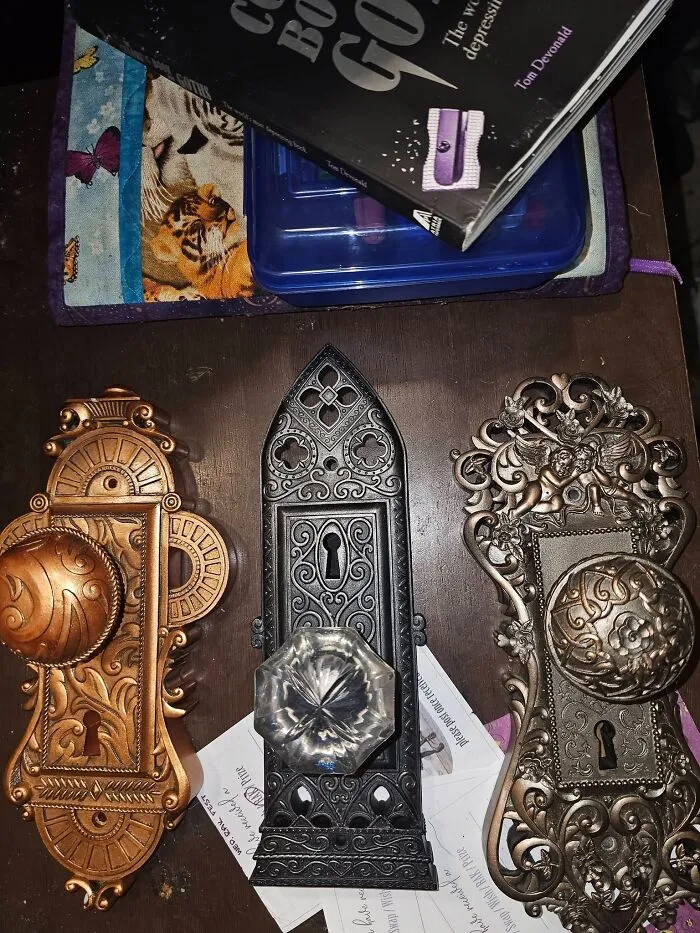 Three vintage ornate metal door plates with intricate designs lined up as rare thrift finds.
