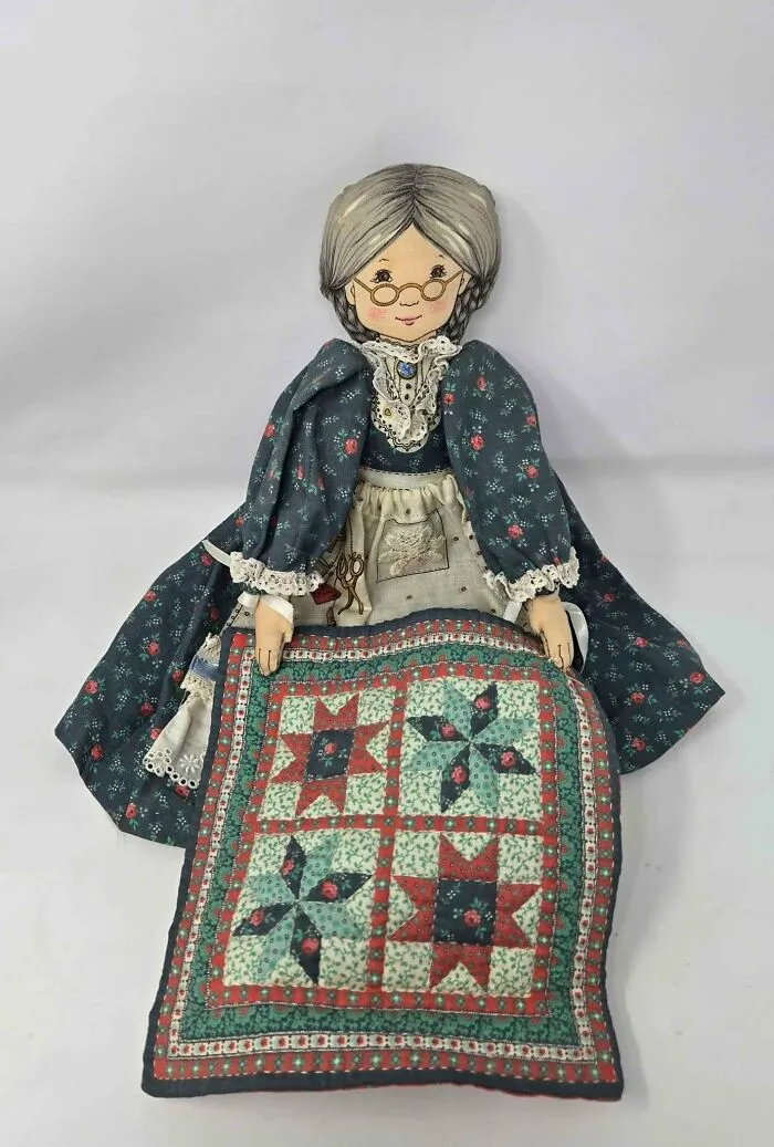 Handmade fabric grandma doll holding a patchwork quilt thrift store find