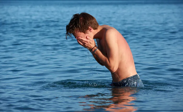 Man washing face in lake water during outdoor activity