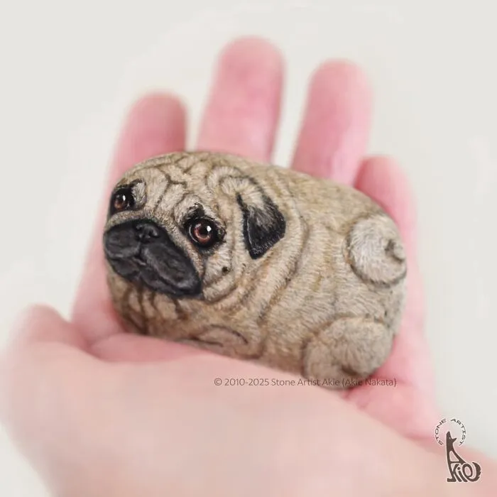 Stone art featuring a lifelike pug dog held in palm