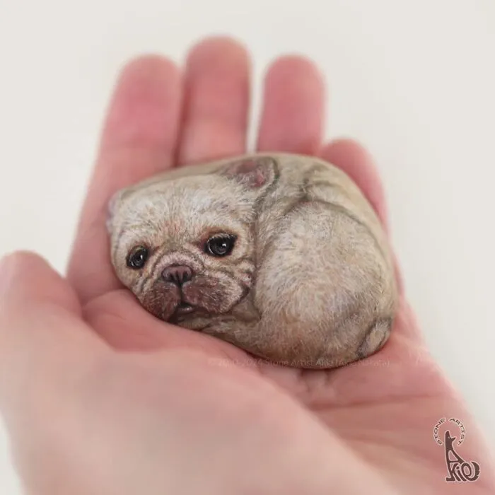 Realistic dog painted on stone held in hand by Japanese artist