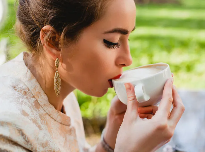 A young woman enjoying a quiet moment drinking coffee, free from helicopter parenting surveillance