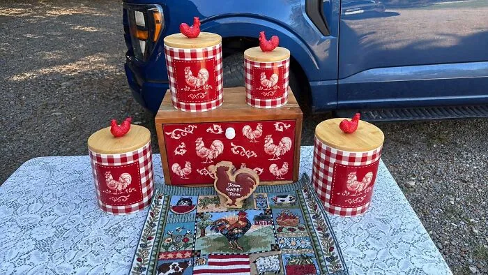 Red rooster canister set displayed on lace tablecloth for thrift store finds