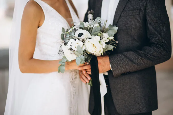 Bride and groom holding wedding bouquet at ceremony