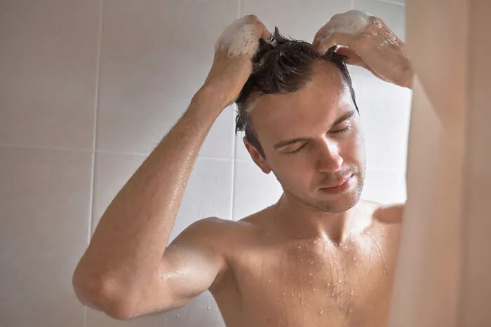 Man washing hair in shower showing refreshing moments in funny revenge stories