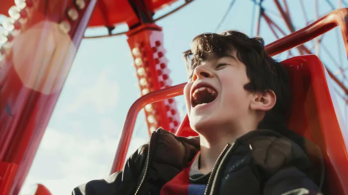 A young boy laughing on an amusement park ride after strangers said a sudden comment.