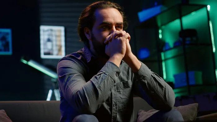Anxious man sitting with hands clasped after hearing something that activated his fight-or-flight response.
