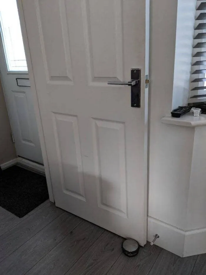 An improperly installed white door that cannot open fully because of a wall, showing a complete fiasco.