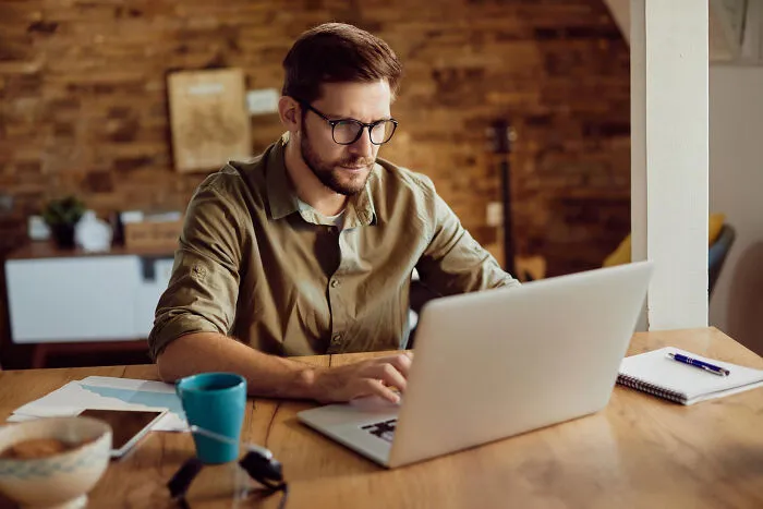 A man working attentively on his laptop, reading real-life divorce stories online.