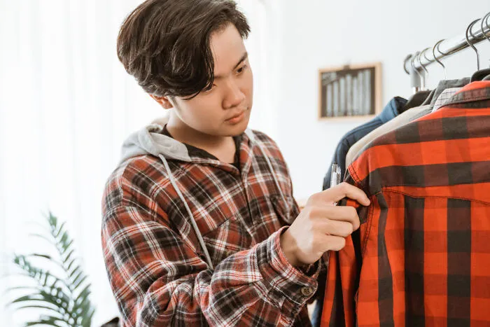 A young man shopping for clothes, symbolizing helicopter parenting over independent choices