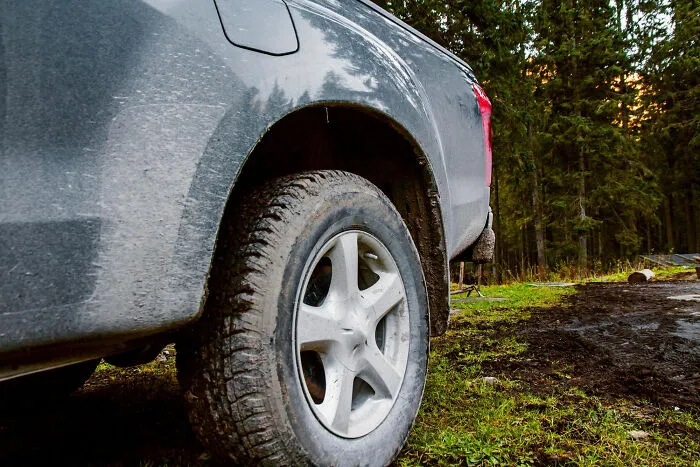 A dirty pickup truck tire on a grassy path, illustrating a moment that made partners question their intelligence.