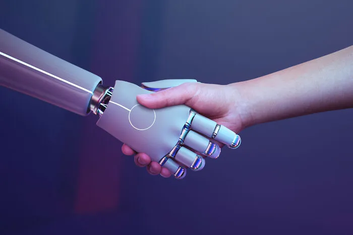 A robotic hand shaking a human hand, illustrating modern movements and lesser-known cults.