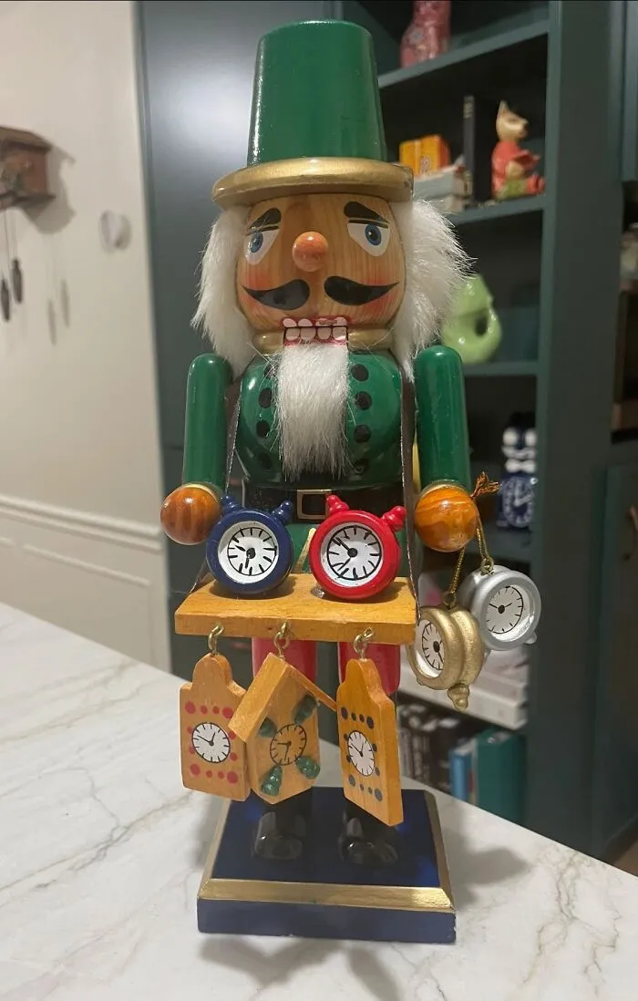 A wooden nutcracker holding miniature clocks and cuckoo clocks, an unusual thrift find.