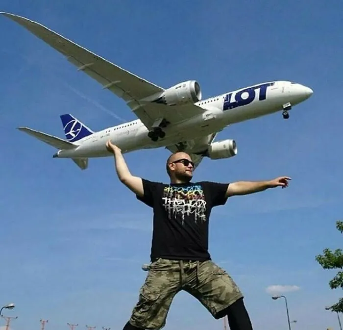 Optical illusion of a man appearing to catch a flying airplane with his bare hand.