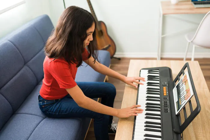 A young student playing a digital piano at home, showcasing frustrated learning from home.