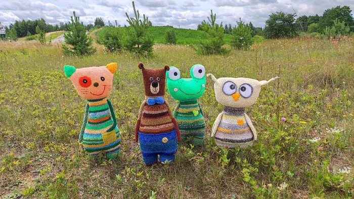 Four handmade crochet creatures standing in grassy field.