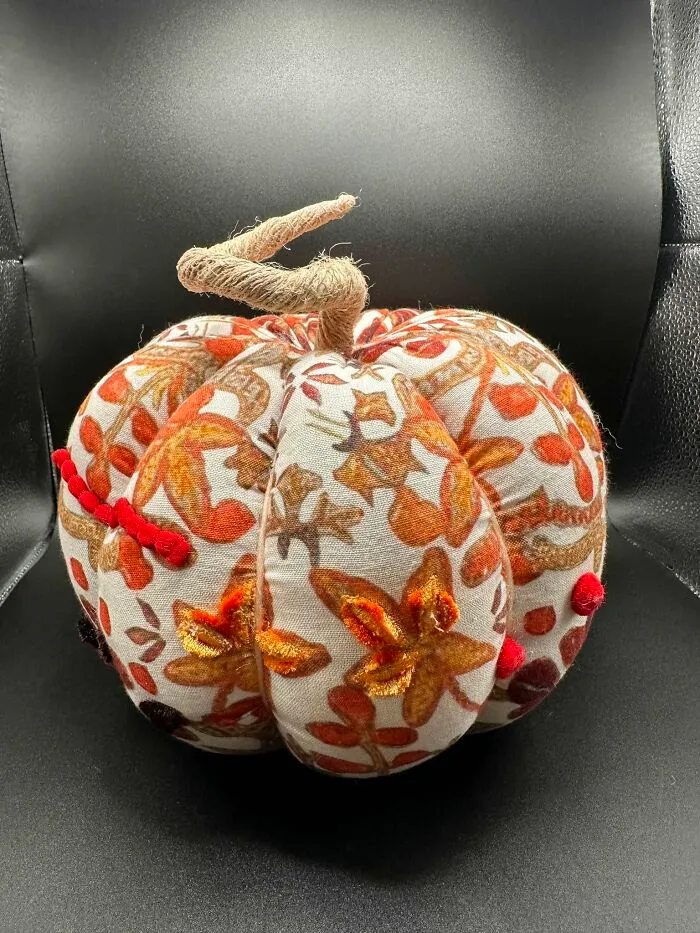 Handmade fabric pumpkin decor with autumn leaf pattern and twine stem