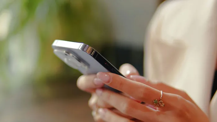 A close-up of a bridesmaid holding a smartphone to read shocking bridezilla stories online.