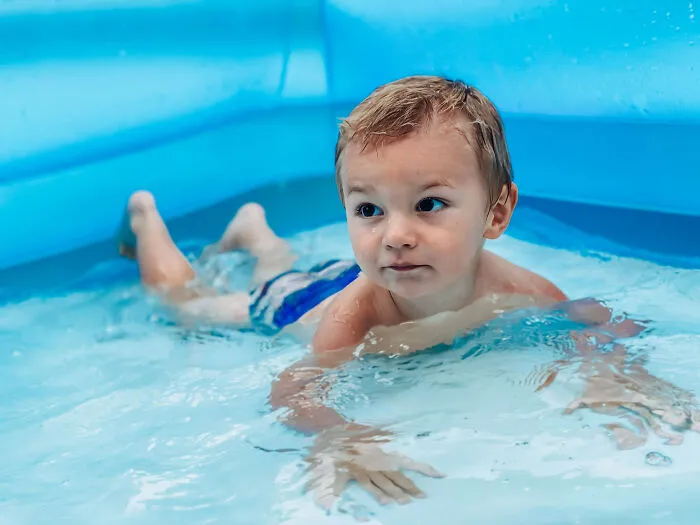 A little boy splashing happily inside an inflatable pool