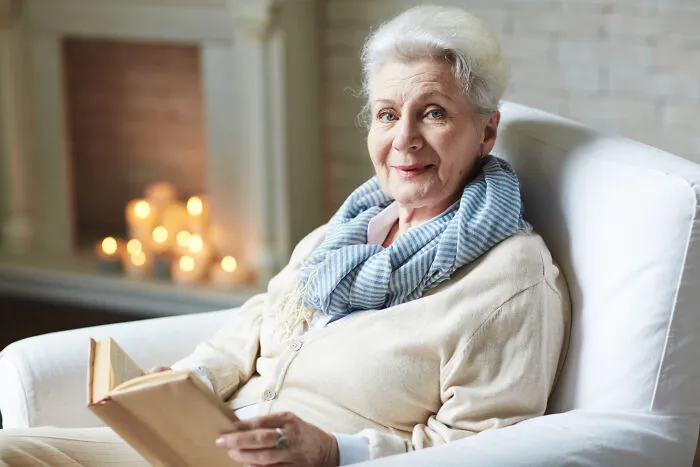 Older woman smiling while reading showing obvious lies about aging