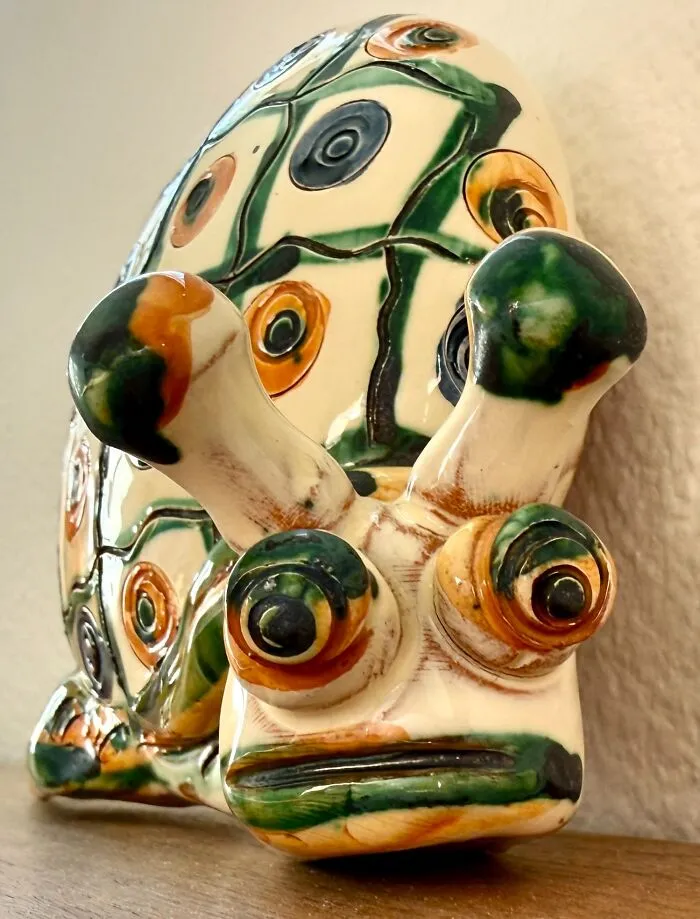 A quirky hand-painted ceramic snail figurine with wide eyes, one of many unique thrift finds resting on a wooden surface.