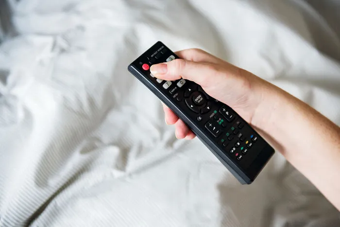A hand holding a TV remote, symbolizing quiet isolation in real-life divorce stories.