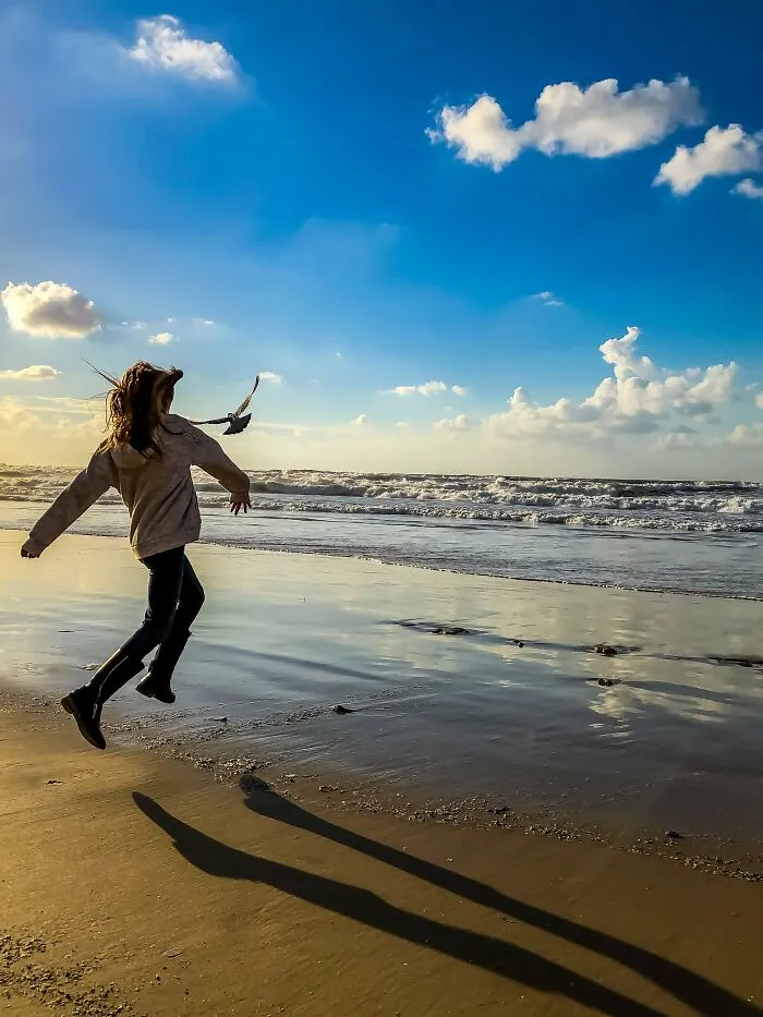 Girl jumping on beach with ocean waves in iPhone photography