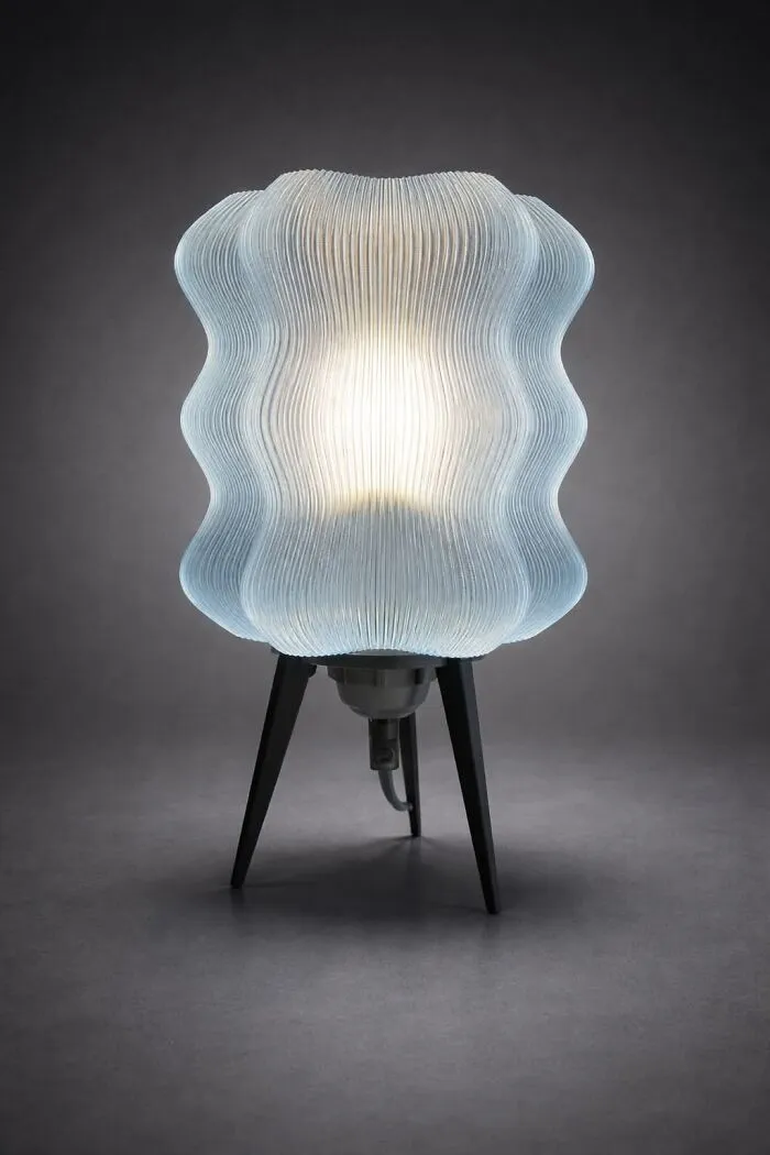 A glowing blue wavy lamp made using 3D prints on a dark background