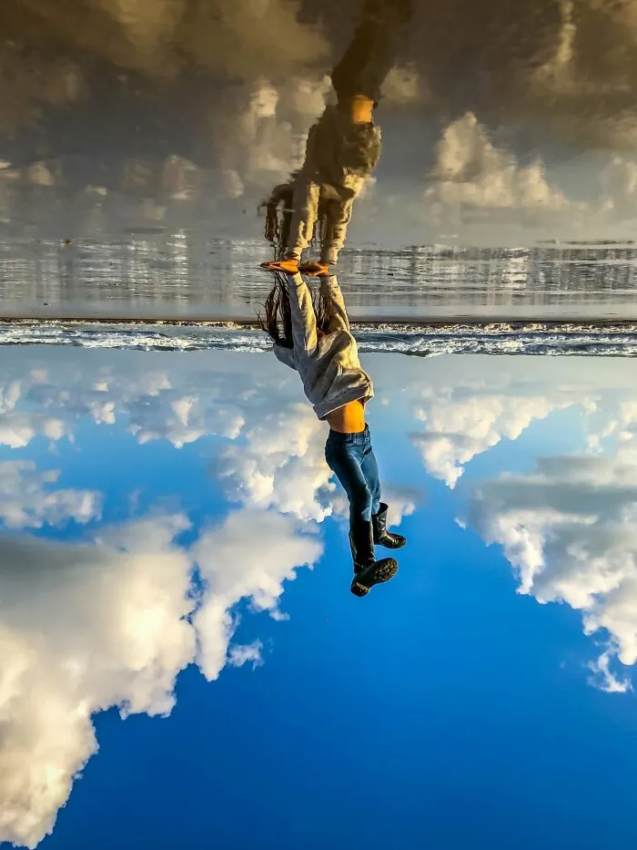 Woman reflection on wet sand beach captured by iPhone photography