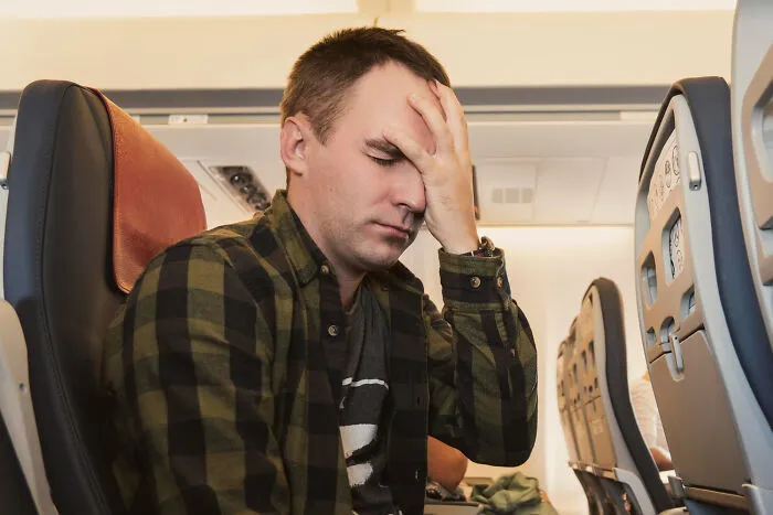 Stressed male passenger sitting in tight cabin seats on commercial flights