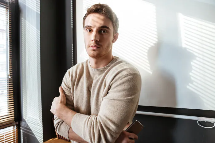 A man standing indoors with arms crossed, reflecting on reasons to skip a second date
